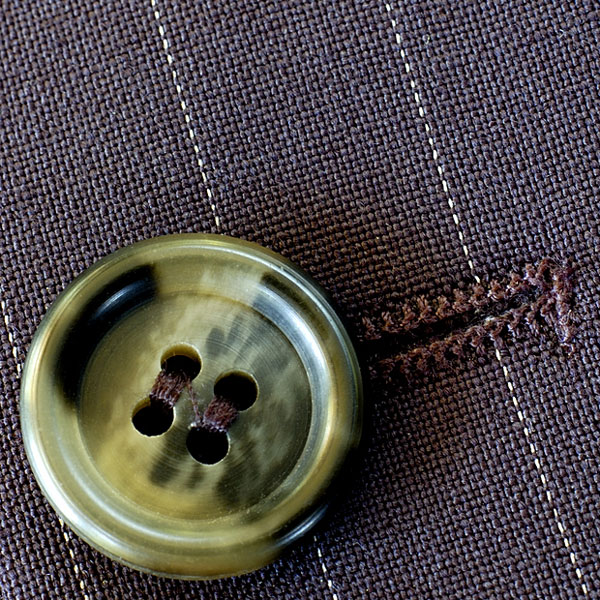 a button and buttonhole on a pin-striped suit (large image)