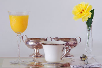 a china teacup, crystal vase, and silver cream and sugar set