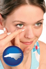 north-carolina map icon and a young woman inserting a contact lens