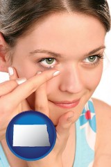 north-dakota map icon and a young woman inserting a contact lens