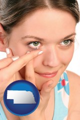 nebraska map icon and a young woman inserting a contact lens