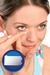 pennsylvania map icon and a young woman inserting a contact lens