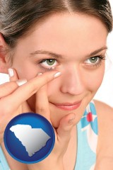 south-carolina map icon and a young woman inserting a contact lens