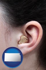 kansas map icon and a woman wearing a hearing aid in her left ear