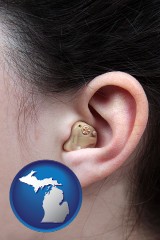 michigan map icon and a woman wearing a hearing aid in her left ear
