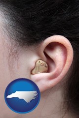 north-carolina map icon and a woman wearing a hearing aid in her left ear