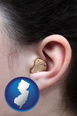 new-jersey map icon and a woman wearing a hearing aid in her left ear