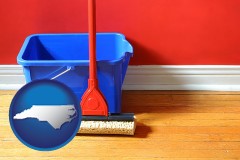 north-carolina map icon and a bucket and mop on a hardwood floor
