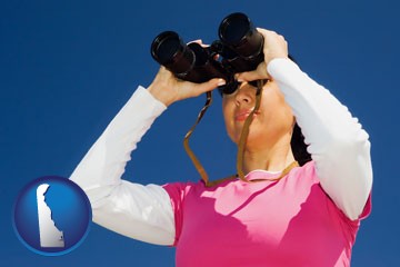 a woman looking through binoculars - with Delaware icon