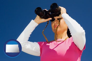 a woman looking through binoculars - with North Dakota icon