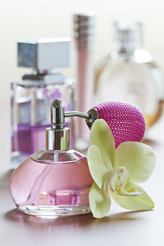 a perfume bottle, with atomizer, and an orchid flower