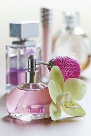 a perfume bottle, with atomizer, and an orchid flower